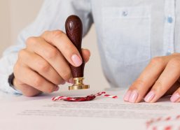 person-using-wax-seal-blurred-certificate